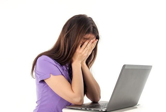 パソコンの前で顔を覆っている女性